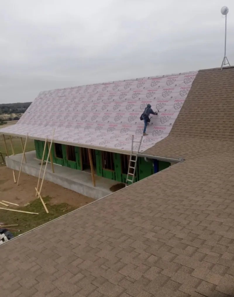 Worker preparing underlayment for a metal roof installation in Walworth